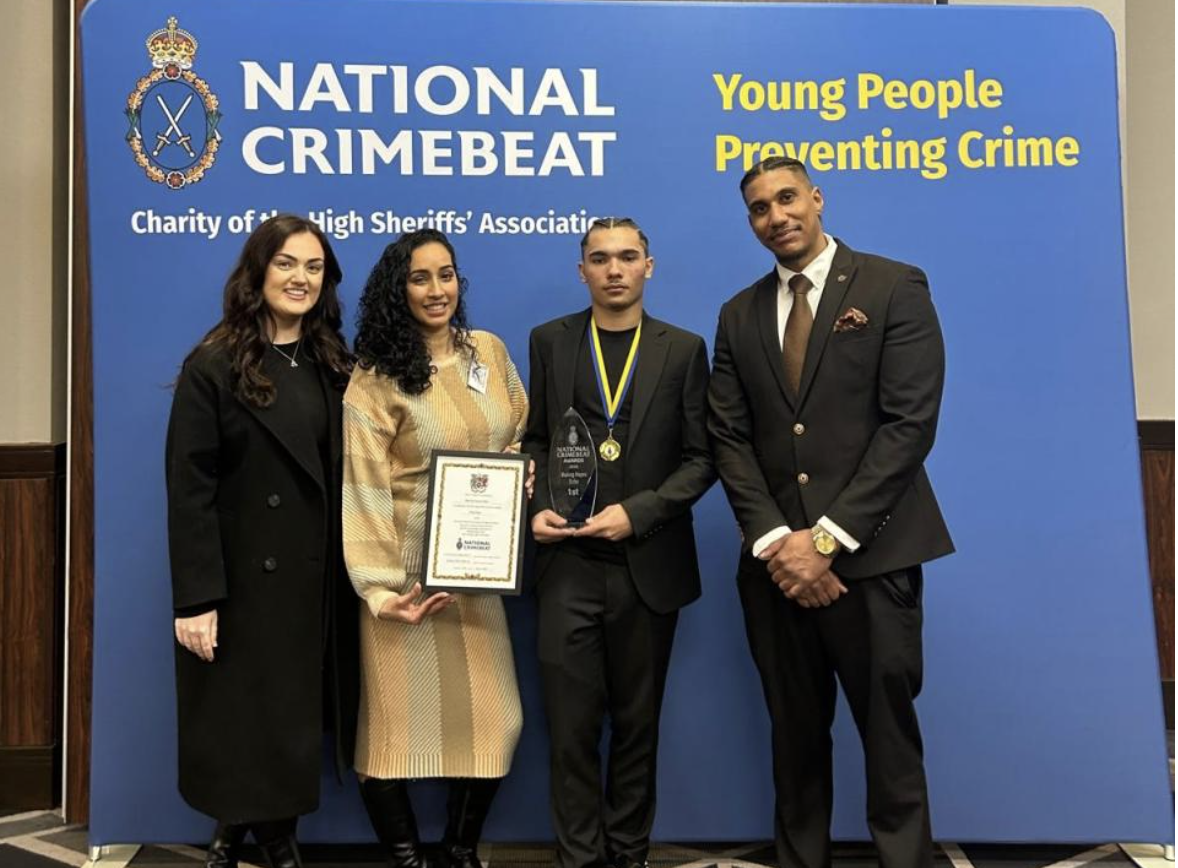 The Making Hayes Safer team receiving 1st place at the National Crimebeat Awards, in front of a National Crimebeat "Young People Preventing Crime" backdrop